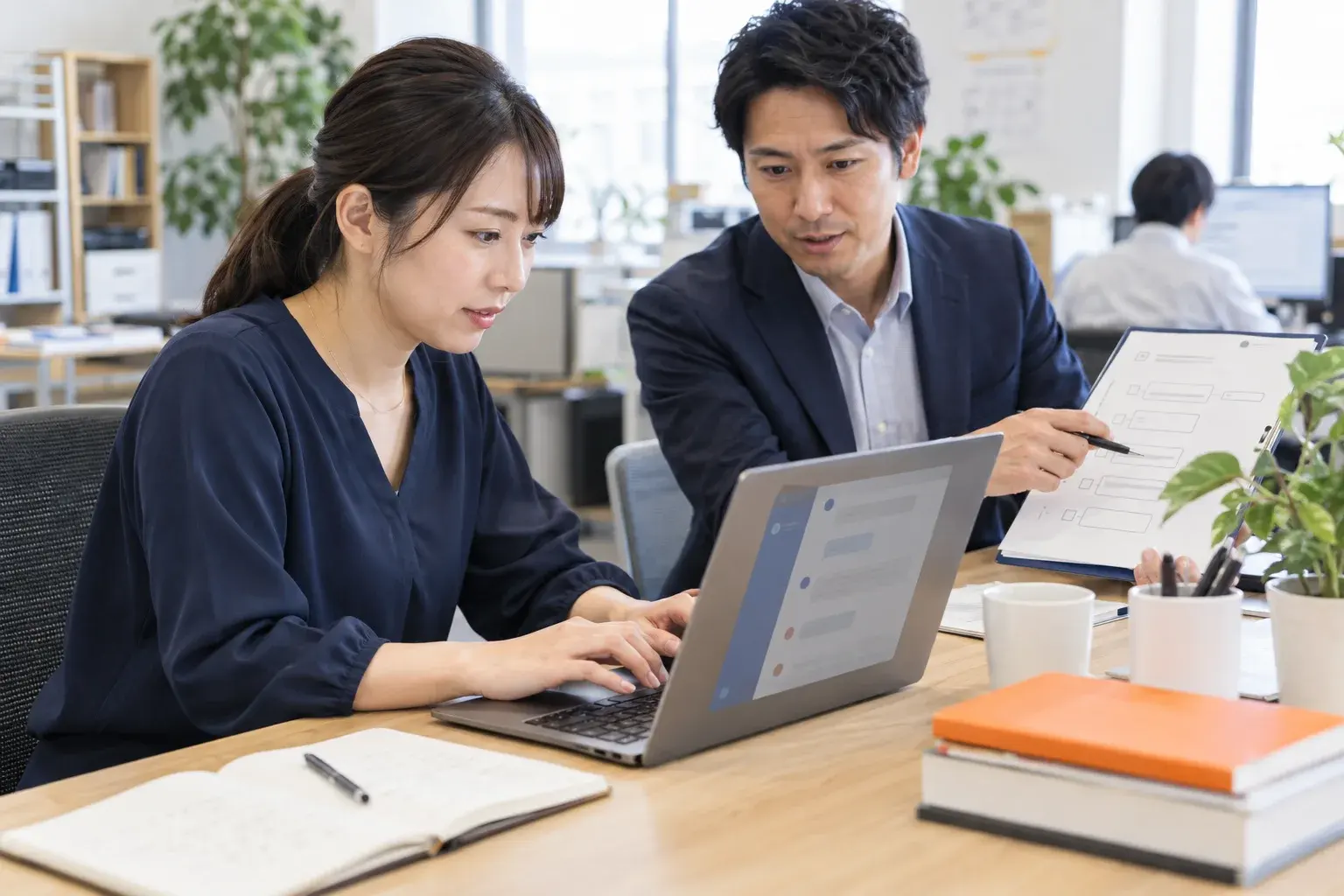 現場担当者がAIを操作し、隣で支援者が業務フローを確認するAI内製化支援のイメージ